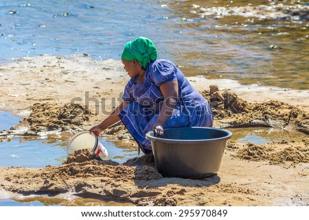 UMkhuze Game Reserve, South Africa - August 24, 2014: African woman collecting water from the river on the road leading to local Game Reserve.