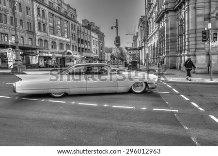 Hobart, Tasmania, Australia - January 16, 2015: Urban scenery in town as retro-style, black and white. A luxury vintage Cadillac running through streets of historic town.