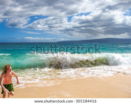 Young boy runs from big waves on Big Beach in Maui island Hawaii, America.