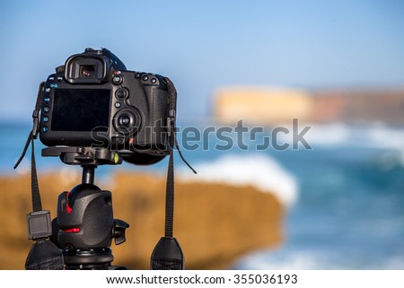 Closeup of a camera on a tripod outdoors. Camera is Canon. background Landscape out of focus. Concept of hobbies, work, travel, tourism and professional photography.