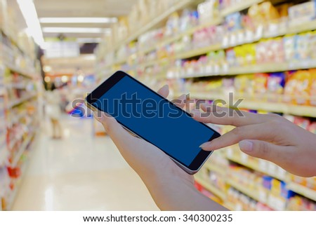 hand using mobile phone in supermarket