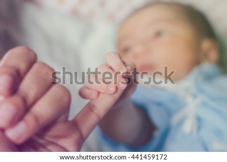 Abstract of blurred newborn baby hand holding mother hand in vintage tone and color filter style : mother day and people concept