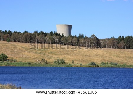 The chimney of a coal-fired power station behind the blue waters of a lake
