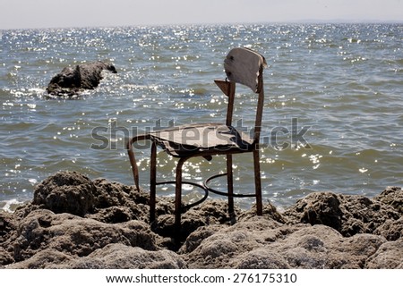 A broken chair sitting alone on the rocky beach of the Salton Sea in Southern California.