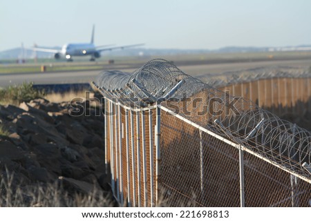 airport security mesh and barbed wire perimeter fence, with airliner.