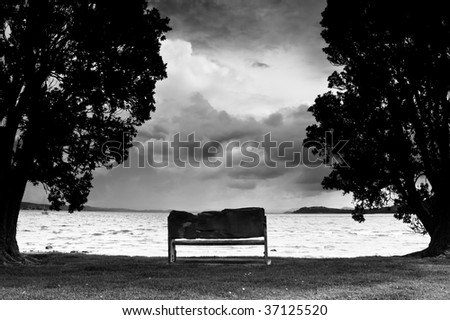 Storm clouds gathering over outdoor seat at beach - black and white.