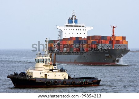 Large container cargo ship and support tug boat, at sea.
