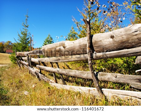 An old wood fence with a green country field behind it