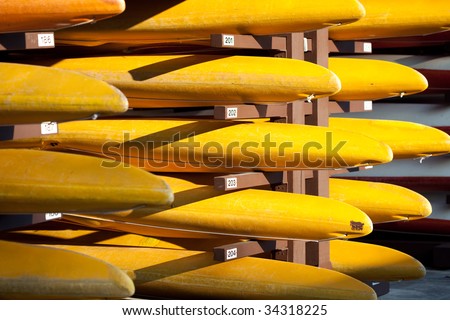 Rows of yellow kayaks on rack for rental