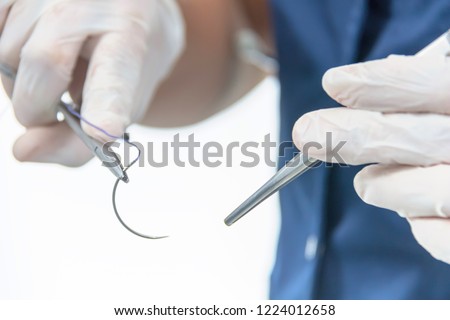 Doctor holding surgical forceps suture needle, suturing material