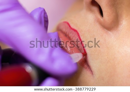 Cosmetologist applying permanent makeup on lips\
Selective focus and shallow Depth of field