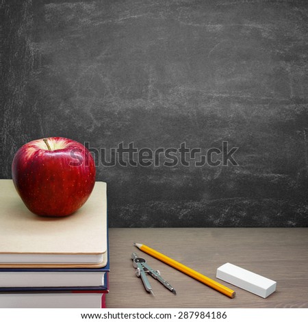 Back To School - A Red Apple on a Pile of Books in front of a Blackboard