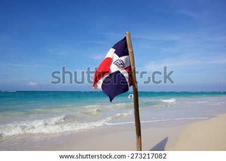 Dominica Republic flag swinging beside the Caribbean beach