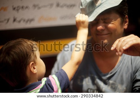 Boy pulls off the hat from his father head