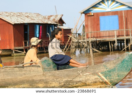 CAMBODIA - APRIL 2005: Cambodian girl and boy sail together on a boat near the fishing village of Tonle Sap Lake around April 2005 in Cambodia. Living conditions in the area are difficult.