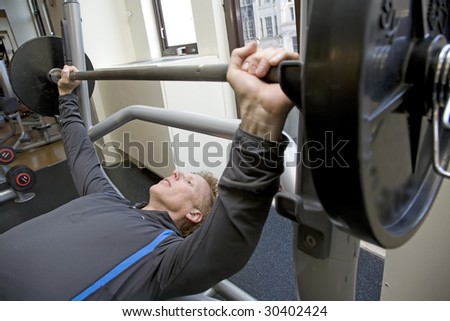 Personal trainer bench pressing weights in a modern gym