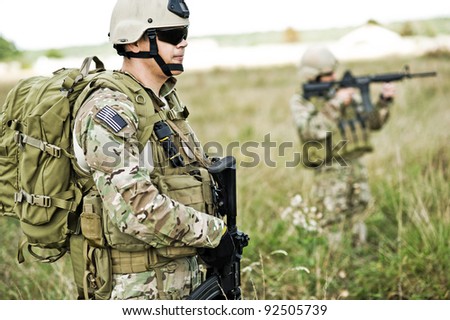 Soldiers  in full gear patrol the area in the desert