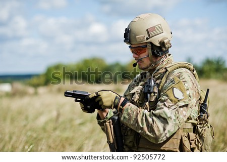 The soldier  in full gear reloads a gun