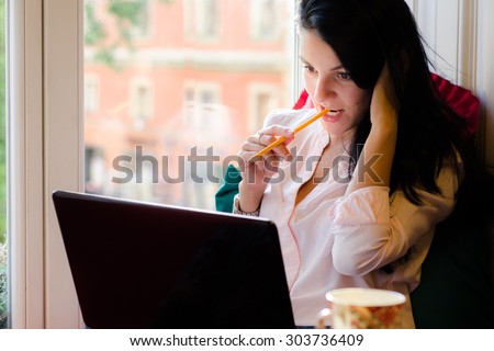 Girl sitting near the window with a laptop