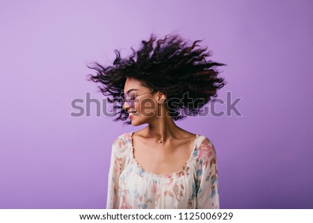 Studio photo of inspired african lady dancing with eyes closed. Indoor portrait of relaxed black girl isolated on purple background.