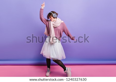 Full-length photo of cute brunette girl dancing in romantic skirt. Studio shot of interested slim woman in black pantyhose and long scarf having fun.