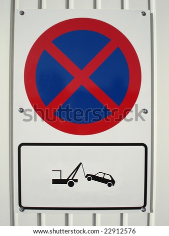No parking sign on white metal garage door with image of a car being taken away.