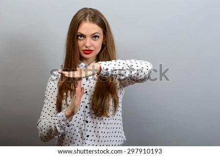 Young woman showing time out hand gesture, frustrated screaming to stop isolated on grey wall background. Too many things to do. Human emotions face expression reaction