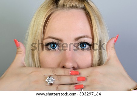 Woman covering her mouth with his hands. On a gray background.