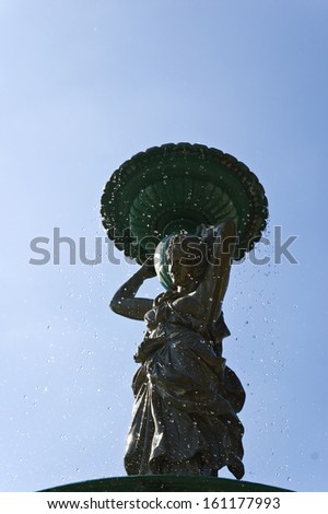 fountain with woman statue water drops and blue sky