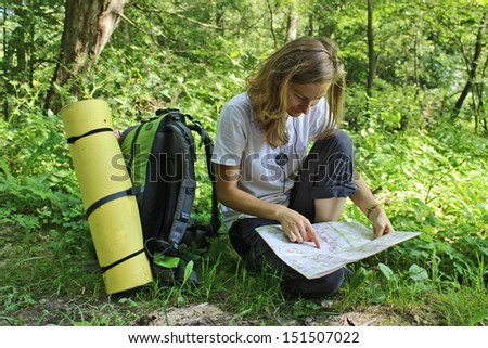 Young Girl Tourist with Backpack in Forest read the Map