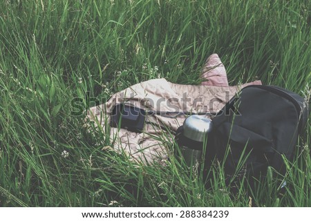 Travel kit - backpack, thermos and camera on the grass