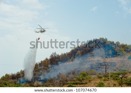 Firefighters helicopter in action, dumping water on a forest fire