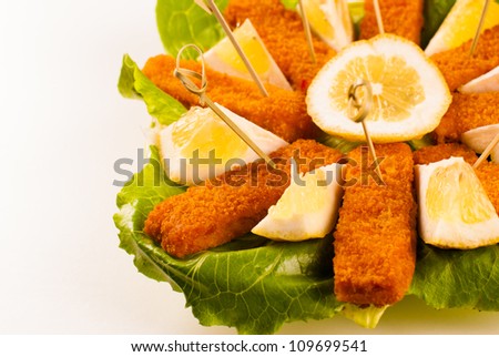 Portion of crunchy fish sticks served with salad and lemon