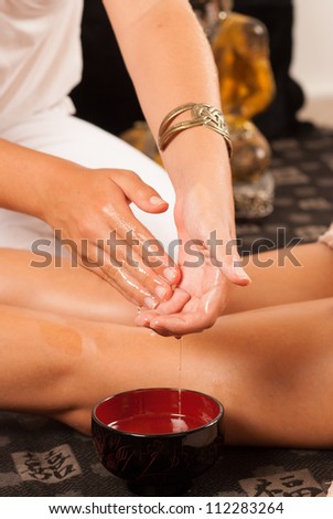 Massage therapist moistening her hands in oil
