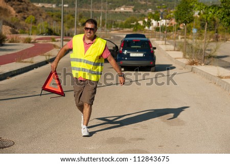Guy carrying a triangle to warn of his breakdown