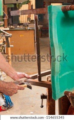 Carpenter hands working at restoring an old chair