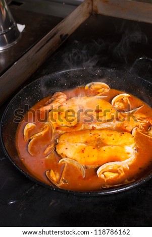 Traditional Spanish hake in cider sauce being cooked