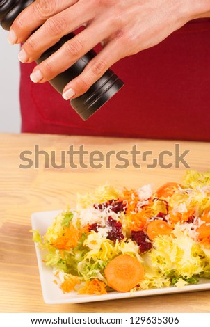 Grinding pepper on a freshly prepared salad