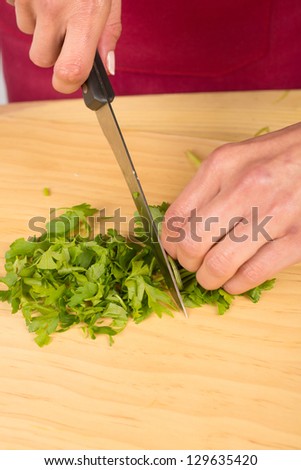 Cutting  fresh parsley leaves on a wooden chopping board