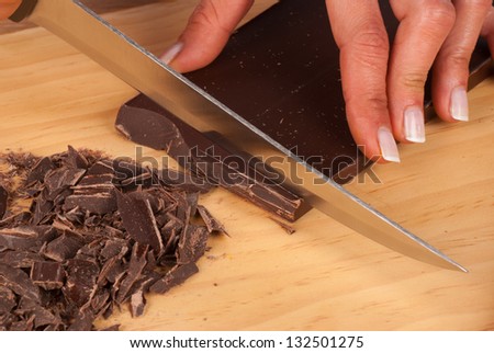 Female hands using a knife to obtain fine black chocolate shavings