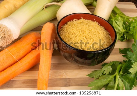 Veggie soup ingredients around a bowl with noodles