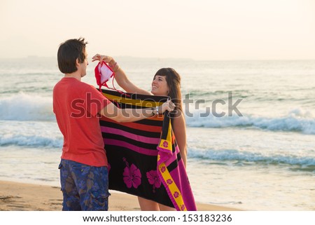 Girl changing clothes on the beach and teasing her boyfriend