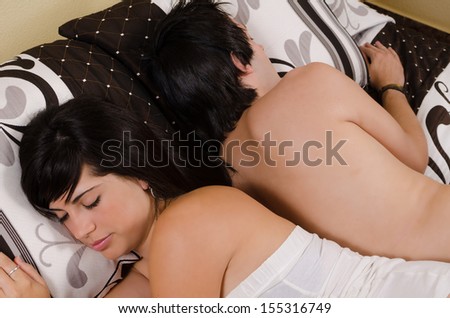 Young couple sleeping in bed back to back