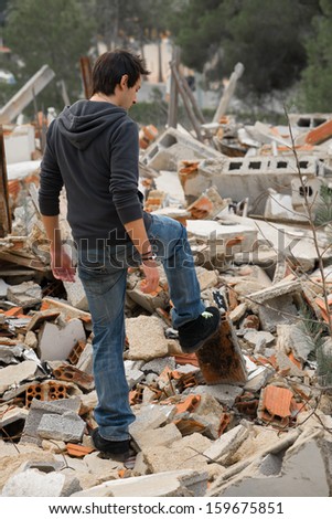 Lonely guy  rummaging  in lots of debris from a pulled down house