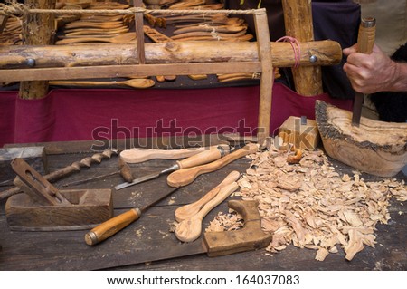 Artisan  hands at work, carving wood into spoons