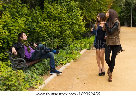 Young women blowing a kiss to  a guy on a park bench