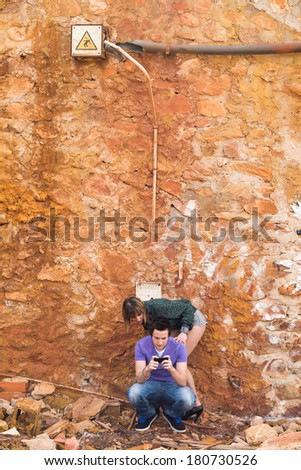 Young adults couple paying attention to their smartphone  inside an industrial ruin