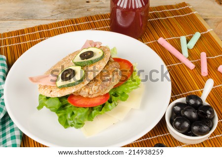 Burger in whole wheat bun decorated as a face, kid food