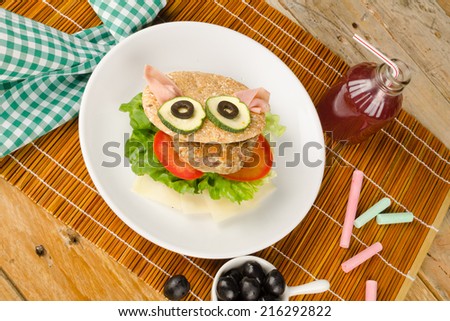 Burger in whole wheat bun decorated as a face, kid food
