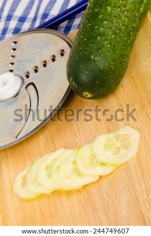Cucumber slices next to a food processor slicing disk